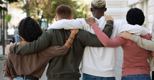 Back view of international group of people making strike on the street, hugging, showing their strong unity, demanding from government saving planet, reducing pollution. Riot, demonstration, strike
