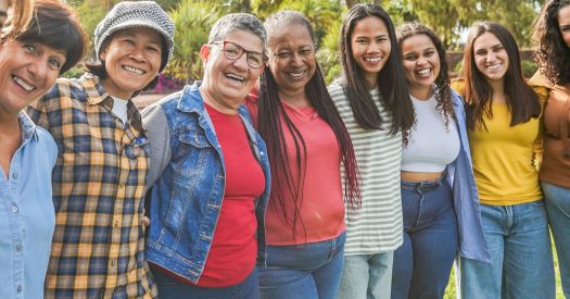 Multi generational women smiling in front of camera - Female multiracial group having fun togheter outdoor - Main focus on woman face with glasses